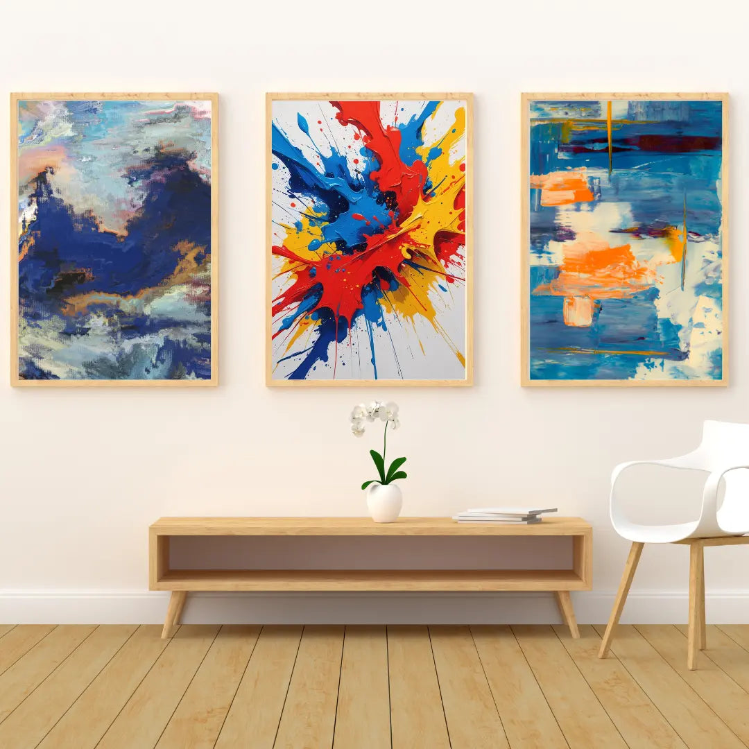 Three abstract paintings on a wall above a wooden console table with a plant and chair.