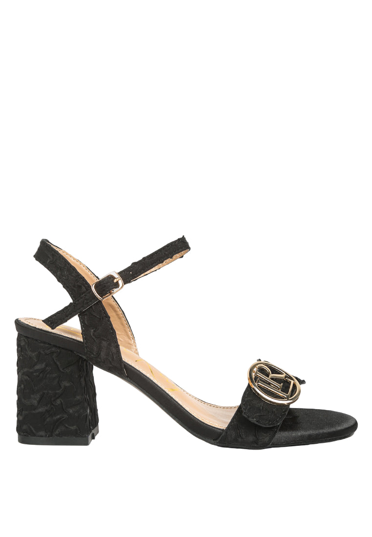 Black sandal with a gold buckle on a white background