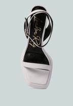 White sandal with black sole on a light blue background