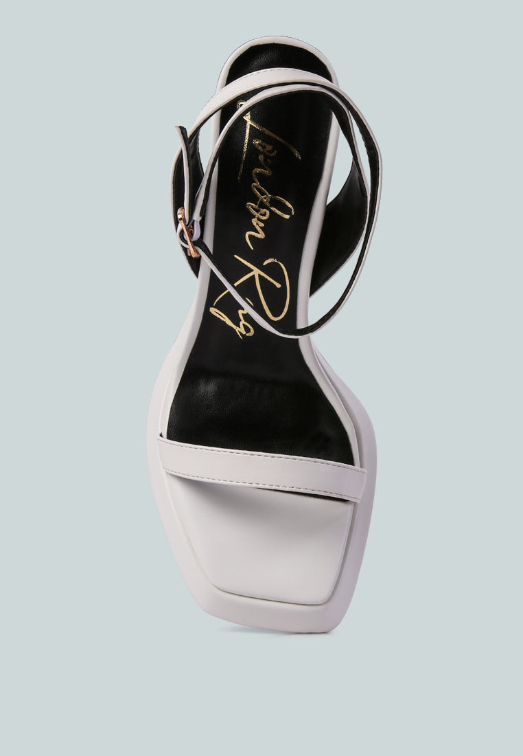 White sandal with black sole on a light blue background