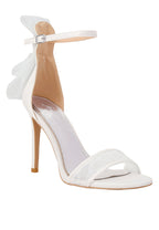 White high-heeled sandal with a clear toe and ankle strap on a light gray background
