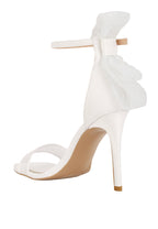 White high-heeled shoe with ruffled design on a light blue background