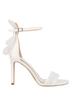 White high-heeled shoe with bow detail on a light gray background