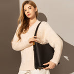 Woman holding a black handbag against a neutral background