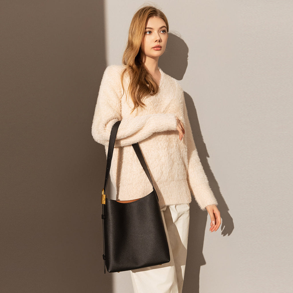 Woman holding a black handbag against a gradient wall