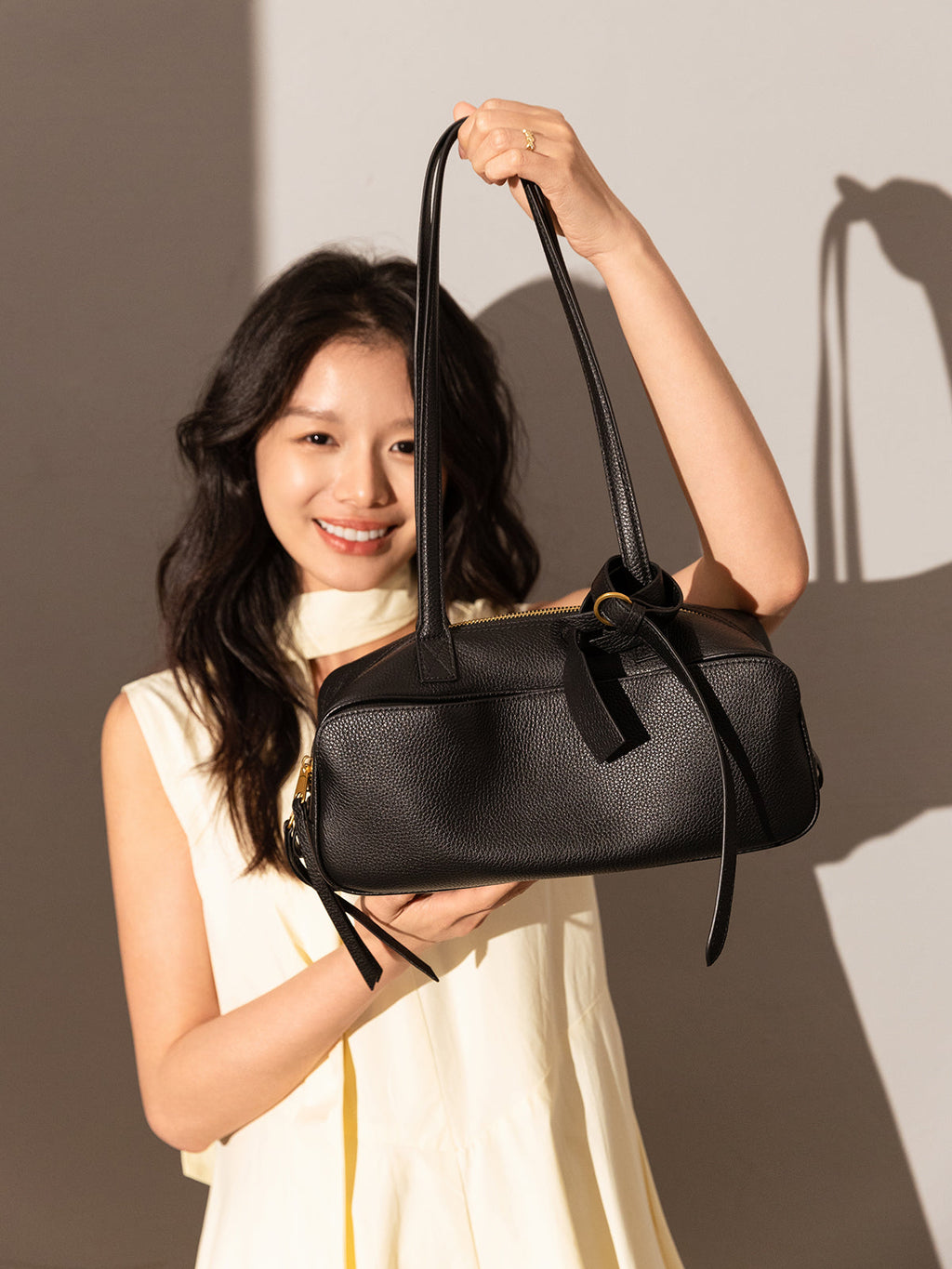 Model showcasing the Mini Rectangular Knot Strap Shoulder Bag in black against a soft backdrop.