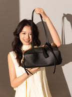 Model showcasing the Mini Rectangular Knot Strap Shoulder Bag in black against a soft backdrop.
