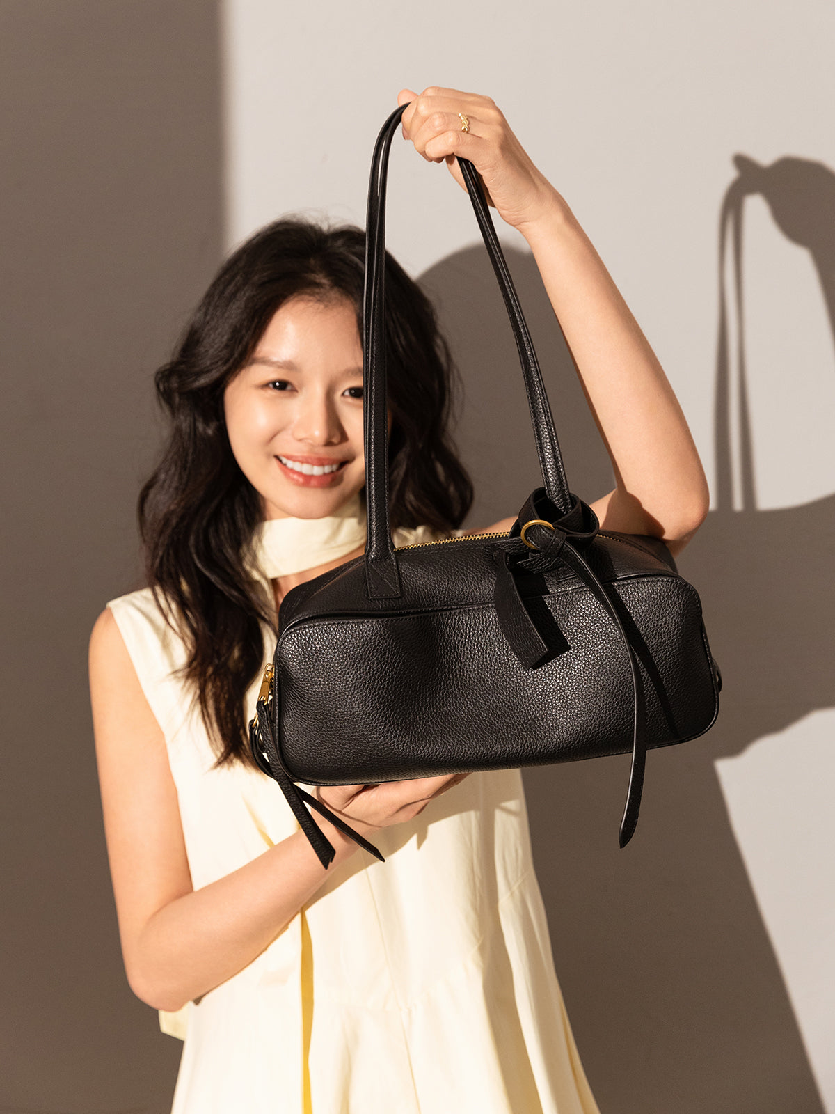 Model showcasing the Mini Rectangular Knot Strap Shoulder Bag in black against a soft backdrop.