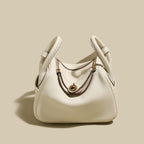 Monte Convertible Shoulder Bag in cream color with gold hardware and unique handle design.