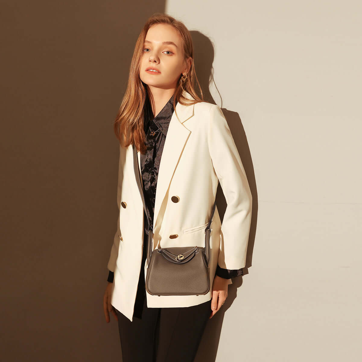 Model showcasing the stylish Monte Convertible Shoulder Bag with a chic white blazer and black outfit.