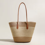 Woven straw tote bag with brown leather handles on a light beige background