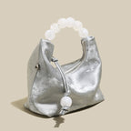 Silver pearl top handle bag with oversized pearl handle, perfect for chic occasions and evening events.
