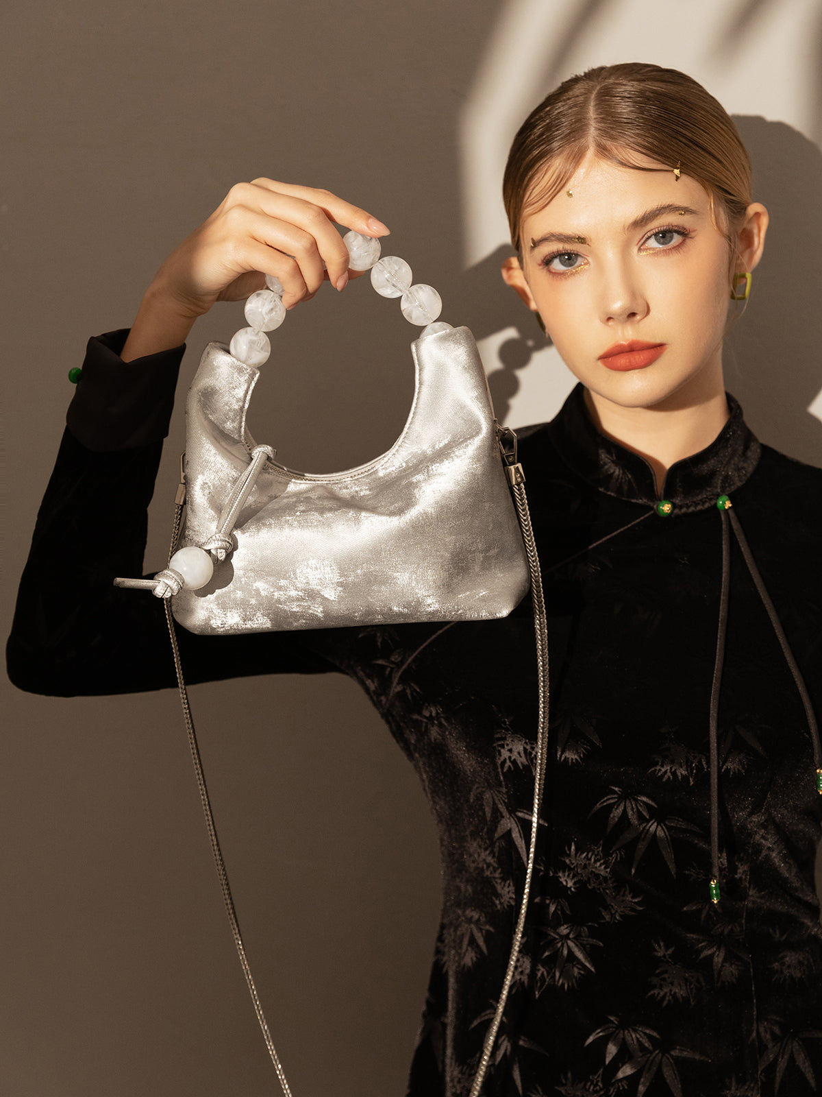 Model showcasing a Silver Pearl Top Handle Bag with a metallic finish and oversized pearl handle.