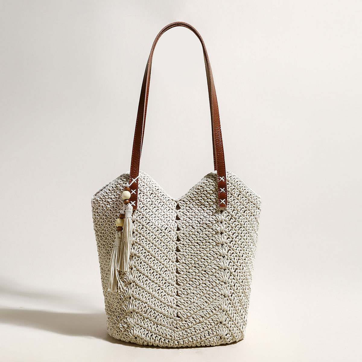 Crocheted handbag with leather handles on a light background