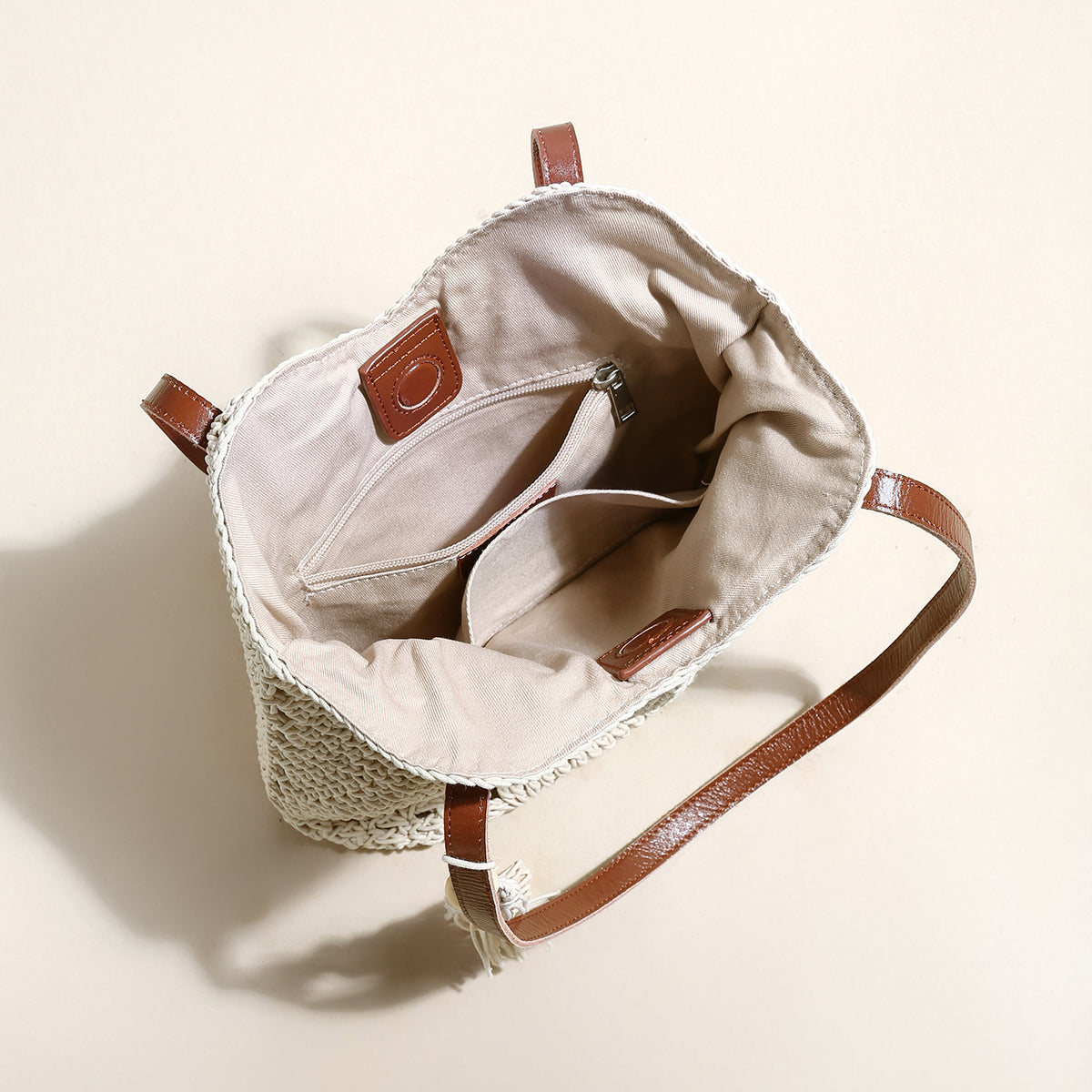 Beige handbag with brown leather accents on a light beige background