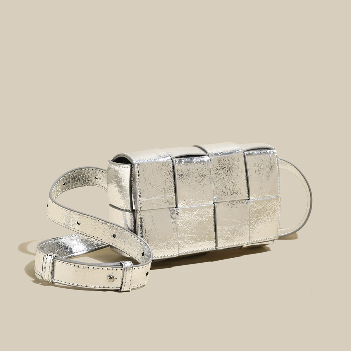 Silver clutch bag with a strap on a beige background
