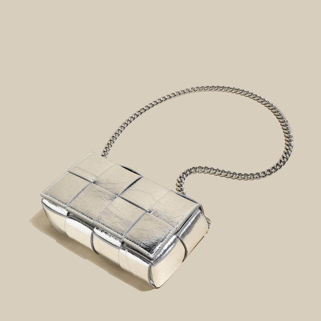 Silver clutch bag with chain strap on a beige background