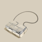 Silver clutch bag with chain strap on a beige background