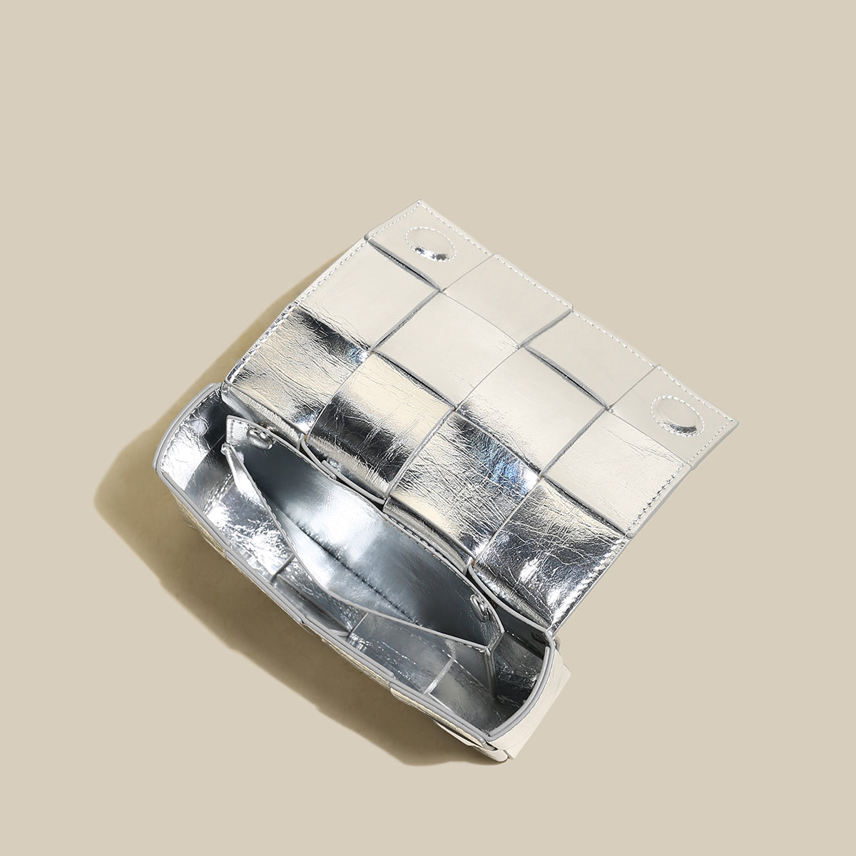 Silver clutch bag with a grid pattern on a beige background