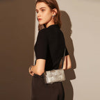 Woman holding a silver handbag against a neutral background
